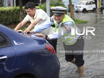 A traffic policeman helps citizens deal with stranded vehicles after a rainstorm in Huai'an, China, on September 14, 2024. (