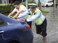 A traffic policeman helps citizens deal with stranded vehicles after a rainstorm in Huai'an, China, on September 14, 2024. (