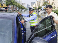 A traffic policeman helps citizens deal with stranded vehicles after a rainstorm in Huai'an, China, on September 14, 2024. (