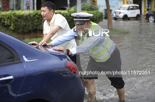 A traffic policeman helps citizens deal with stranded vehicles after a rainstorm in Huai'an, China, on September 14, 2024. 