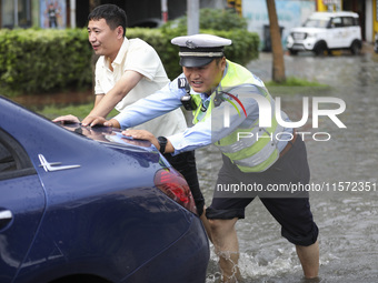 A traffic policeman helps citizens deal with stranded vehicles after a rainstorm in Huai'an, China, on September 14, 2024. (