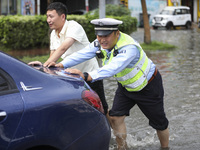 A traffic policeman helps citizens deal with stranded vehicles after a rainstorm in Huai'an, China, on September 14, 2024. (