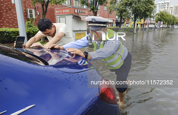 A traffic policeman helps citizens deal with stranded vehicles after a rainstorm in Huai'an, China, on September 14, 2024. 