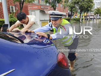 A traffic policeman helps citizens deal with stranded vehicles after a rainstorm in Huai'an, China, on September 14, 2024. (