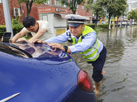 A traffic policeman helps citizens deal with stranded vehicles after a rainstorm in Huai'an, China, on September 14, 2024. (