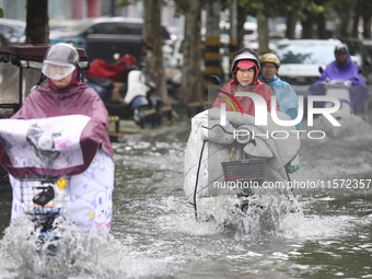 People travel in the rain in Huai'an, China, on September 14, 2024. (