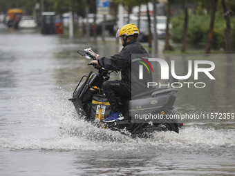 People travel in the rain in Huai'an, China, on September 14, 2024. (