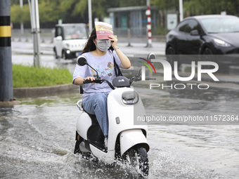 People travel in the rain in Huai'an, China, on September 14, 2024. (