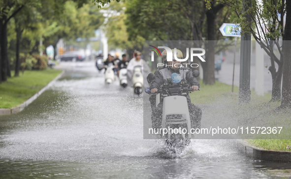 People travel in the rain in Huai'an, China, on September 14, 2024. 