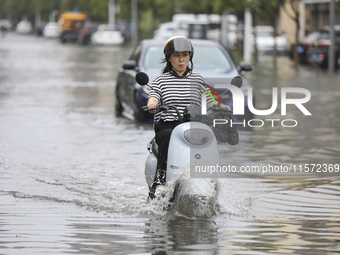 People travel in the rain in Huai'an, China, on September 14, 2024. (