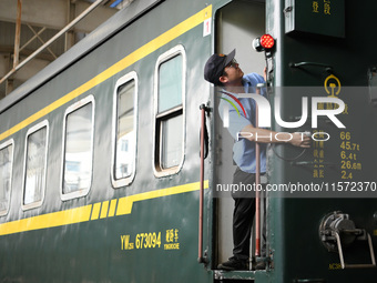 Workers inspect a bullet train in Jiujiang, China, on September 13, 2024. (