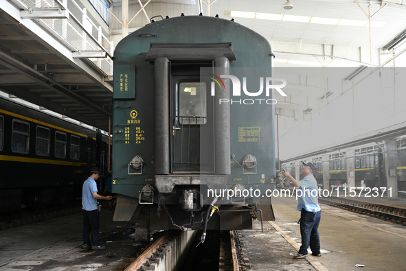 Workers inspect a bullet train in Jiujiang, China, on September 13, 2024. 