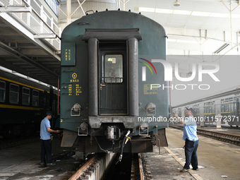 Workers inspect a bullet train in Jiujiang, China, on September 13, 2024. (