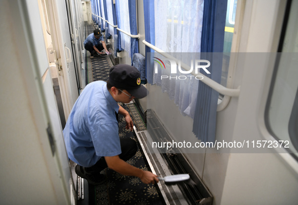 Workers inspect a bullet train in Jiujiang, China, on September 13, 2024. 