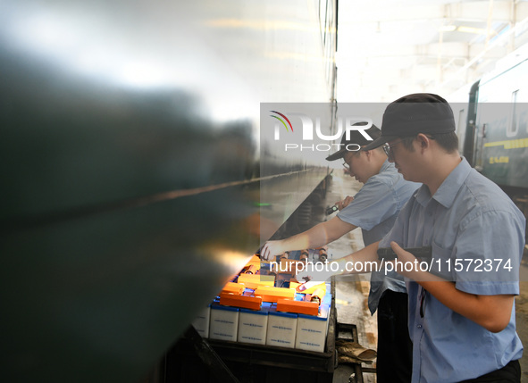 Workers inspect a bullet train in Jiujiang, China, on September 13, 2024. 