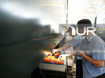 Workers inspect a bullet train in Jiujiang, China, on September 13, 2024. (