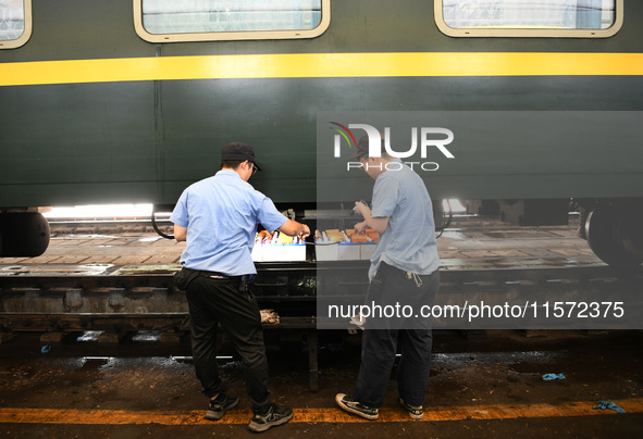 Workers inspect a bullet train in Jiujiang, China, on September 13, 2024. 