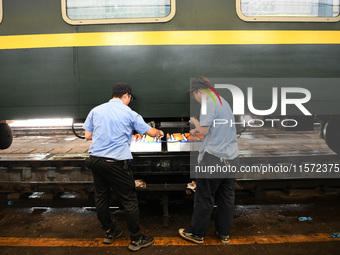 Workers inspect a bullet train in Jiujiang, China, on September 13, 2024. (