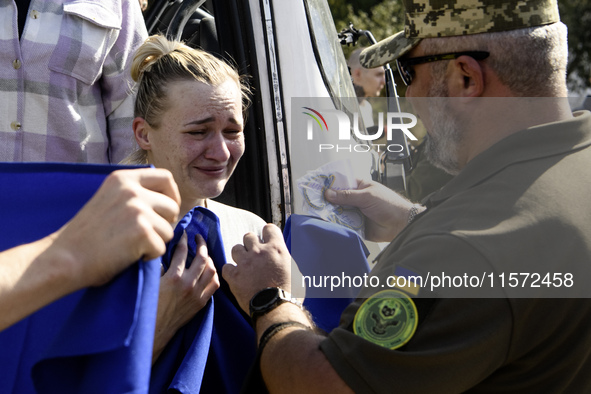 Ukrainian prisoners of war (POWs) react as they exit a bus as forty-nine civilian and military Ukrainians return to Ukraine from captivity i...