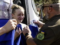 Ukrainian prisoners of war (POWs) react as they exit a bus as forty-nine civilian and military Ukrainians return to Ukraine from captivity i...