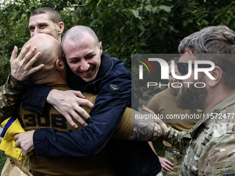 A fellow soldier hugs a Ukrainian prisoner of war (POW) who returns from captivity as forty-nine civilian and military Ukrainians return to...