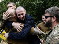 A fellow soldier hugs a Ukrainian prisoner of war (POW) who returns from captivity as forty-nine civilian and military Ukrainians return to...