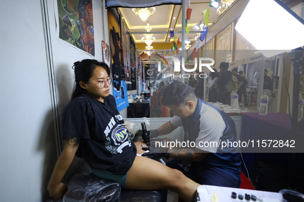 An artist (R) inks a tattoo on the body of an enthusiast (L) during the Himalayan Tattoo Convention in Lalitpur, Nepal, on August 14, 2024....