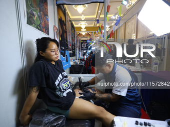 An artist (R) inks a tattoo on the body of an enthusiast (L) during the Himalayan Tattoo Convention in Lalitpur, Nepal, on August 14, 2024....