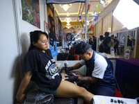 An artist (R) inks a tattoo on the body of an enthusiast (L) during the Himalayan Tattoo Convention in Lalitpur, Nepal, on August 14, 2024....