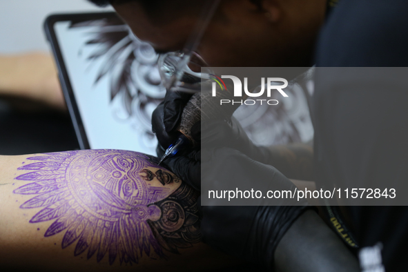 An artist inks a tattoo on the body of an enthusiast during the Himalayan Tattoo Convention in Lalitpur, Nepal, on August 14, 2024. The tatt...