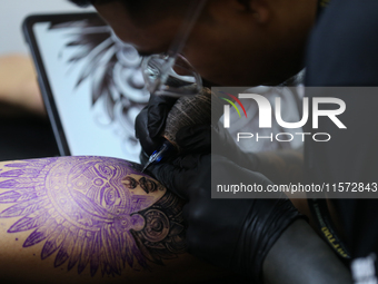 An artist inks a tattoo on the body of an enthusiast during the Himalayan Tattoo Convention in Lalitpur, Nepal, on August 14, 2024. The tatt...