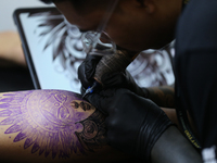 An artist inks a tattoo on the body of an enthusiast during the Himalayan Tattoo Convention in Lalitpur, Nepal, on August 14, 2024. The tatt...