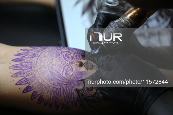 An artist inks a tattoo on the body of an enthusiast during the Himalayan Tattoo Convention in Lalitpur, Nepal, on August 14, 2024. The tatt...