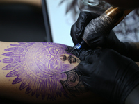 An artist inks a tattoo on the body of an enthusiast during the Himalayan Tattoo Convention in Lalitpur, Nepal, on August 14, 2024. The tatt...