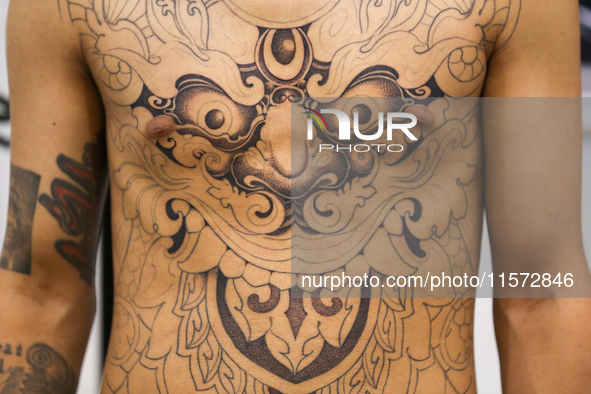 A person poses for a photo showing his tattooed body, which features Hindu Lord Bhairav, during the Himalayan Tattoo Convention in Lalitpur,...