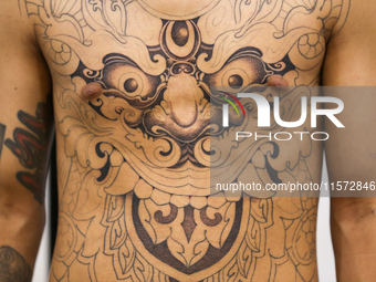 A person poses for a photo showing his tattooed body, which features Hindu Lord Bhairav, during the Himalayan Tattoo Convention in Lalitpur,...