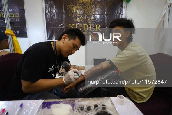 An artist (L) inks a tattoo on the body of an enthusiast (R) during the Himalayan Tattoo Convention in Lalitpur, Nepal, on August 14, 2024....