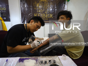 An artist (L) inks a tattoo on the body of an enthusiast (R) during the Himalayan Tattoo Convention in Lalitpur, Nepal, on August 14, 2024....