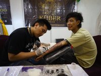 An artist (L) inks a tattoo on the body of an enthusiast (R) during the Himalayan Tattoo Convention in Lalitpur, Nepal, on August 14, 2024....