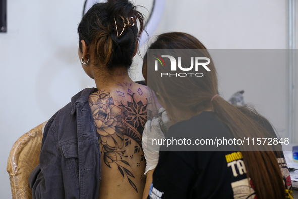 An artist (R) inks a tattoo on the body of an enthusiast (L) during the Himalayan Tattoo Convention in Lalitpur, Nepal, on August 14, 2024....