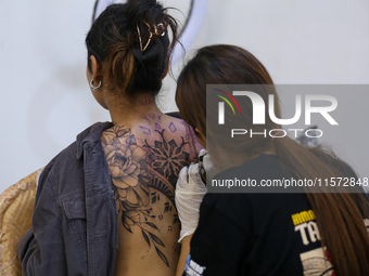 An artist (R) inks a tattoo on the body of an enthusiast (L) during the Himalayan Tattoo Convention in Lalitpur, Nepal, on August 14, 2024....