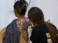 An artist (R) inks a tattoo on the body of an enthusiast (L) during the Himalayan Tattoo Convention in Lalitpur, Nepal, on August 14, 2024....