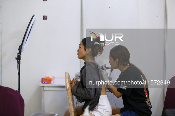 An artist (R) inks a tattoo on the body of an enthusiast (L) during the Himalayan Tattoo Convention in Lalitpur, Nepal, on August 14, 2024....