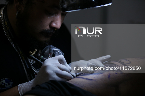 An artist inks a tattoo on the body of an enthusiast during the Himalayan Tattoo Convention in Lalitpur, Nepal, on August 14, 2024. The tatt...