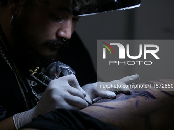 An artist inks a tattoo on the body of an enthusiast during the Himalayan Tattoo Convention in Lalitpur, Nepal, on August 14, 2024. The tatt...