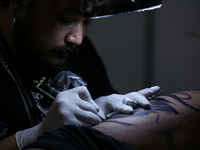 An artist inks a tattoo on the body of an enthusiast during the Himalayan Tattoo Convention in Lalitpur, Nepal, on August 14, 2024. The tatt...