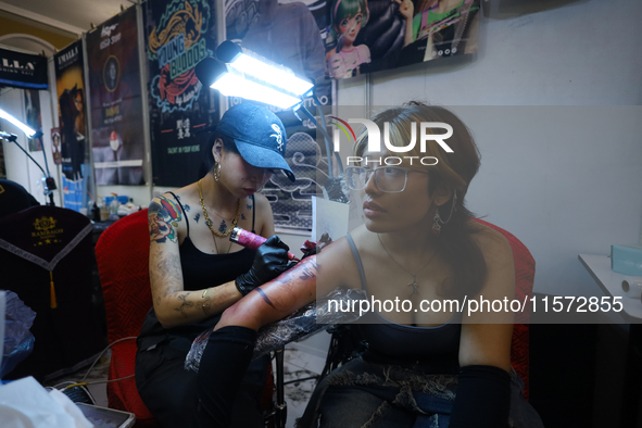 An artist (L) inks a tattoo on the body of an enthusiast (R) during the Himalayan Tattoo Convention in Lalitpur, Nepal, on August 14, 2024....