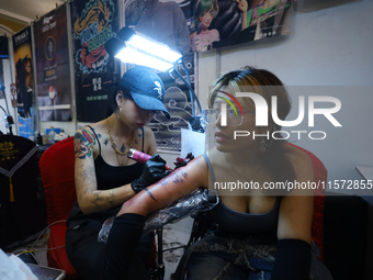 An artist (L) inks a tattoo on the body of an enthusiast (R) during the Himalayan Tattoo Convention in Lalitpur, Nepal, on August 14, 2024....