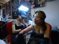 An artist (L) inks a tattoo on the body of an enthusiast (R) during the Himalayan Tattoo Convention in Lalitpur, Nepal, on August 14, 2024....