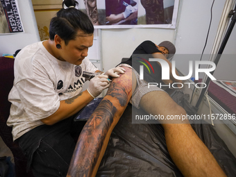 An artist (L) inks a tattoo on the body of an enthusiast (R) during the Himalayan Tattoo Convention in Lalitpur, Nepal, on August 14, 2024....